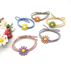 Close-up of five colorful daisy hair ties in blue, pink, and grey on a clean background