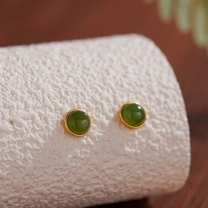 Macro shot of S925 silver studs featuring green jadeite stones on a textured surface