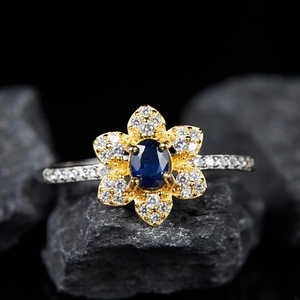 S925 sterling silver flower ring with blue gemstone and white zircon on stone background