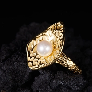 Macro shot of large white freshwater pearl set on textured golden organic petal band