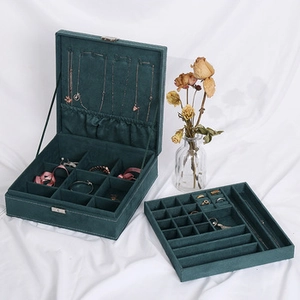 Detail view of open velvet jewelry box in dark green with multi-layer storage compartments