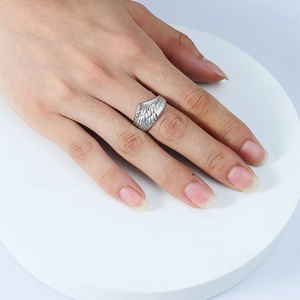 Detailed view of silver angel wing ring with intricate feather texture on hand
