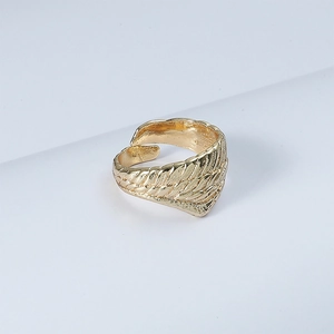 Macro detail of adjustable golden angel wing ring showing intricate feather texture