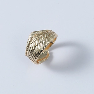 Detailed top view of gold feather textured adjustable open ring on light blue surface