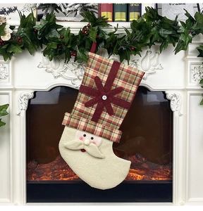 Detail of Santa Claus Christmas stocking with plaid fabric and cream faux fur by fireplace
