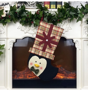 Detail of Christmas stocking with 3D penguin mascot hanging on a festive mantelpiece
