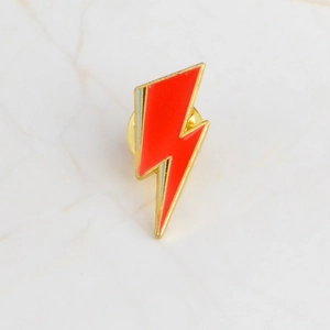 Detail of red lightning bolt brooch with gold metal trim and butterfly clutch backing