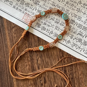 Detail of bohemian woven belt with turquoise beads and flower accents on vintage paper