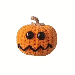 Handmade crochet orange Halloween pumpkin plush toy with black button eyes on white background