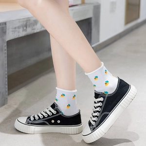 White cotton mid-calf socks with pineapple pattern and ruffled edges worn with black shoes