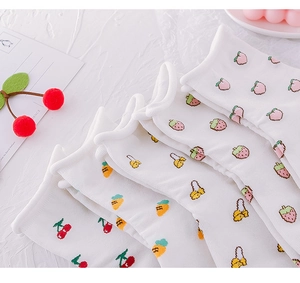 Detail view of five pairs of white cotton socks with cute fruit patterns and ruffled edges