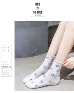 Close-up of white cotton mid-calf socks with pink peach patterns and rolled edges