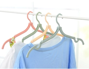 Close-up of colorful folding travel hangers in pink, green, and beige on a white rod