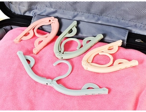 Foldable travel clothes hangers in four pastel colors shown inside a suitcase setup