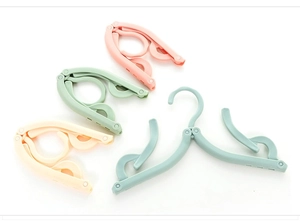 Detail of four foldable travel hangers in pastel colors showing both open and closed states