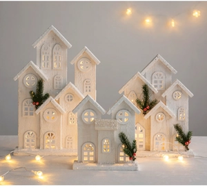 Detail of glowing wooden Christmas cabins with snow glitter finish and warm LED light