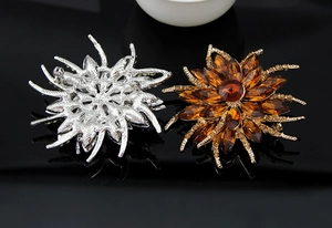 Detailed view of floral crystal brooches with gold and silver alloy bases on black mirror