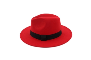 Detailed view of a red wool fedora hat with a classic black ribbon on a white background