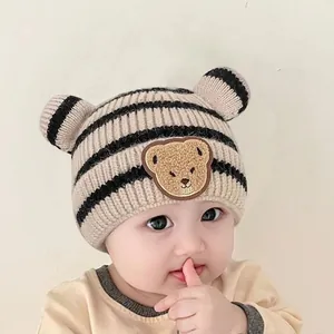 Détail du bonnet rayé pour bébé avec écusson ourson et petites oreilles en relief