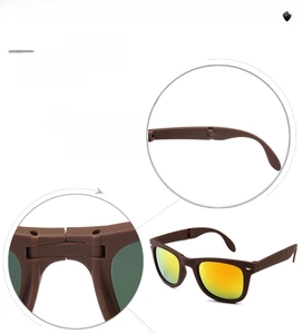 Detail of folding mechanism and orange gradient lenses on matte brown sunglasses