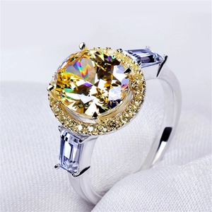 Luxury ring with round yellow zircon center stone and blue sapphire side stones on white fabric