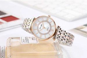 Detail of a rose gold and silver stainless steel watch on a luxury perfume bottle