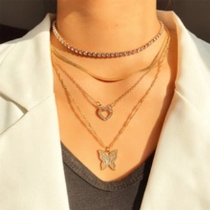 Close-up of bohemian gold layered necklaces with butterfly and heart pendants on model