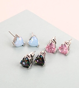 Close-up of three heart-shaped stud earrings in blue opal and colorful zircon on a stand