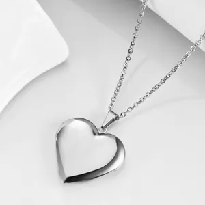 Close-up of a polished silver heart locket necklace with a hinge on a white background
