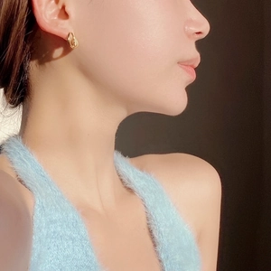 Close-up of elegant gold twisted hoop earrings worn by a model in soft lighting