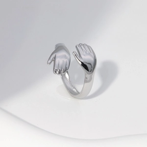 Macro shot of silver stainless steel hug ring showing detailed hand clasp design