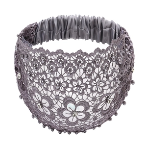 Detail view of grey lace headband with pearl and rhinestone accents on white background