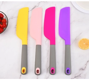 Flat lay of colorful silicone spatulas on marble surface with baking ingredients