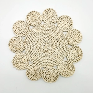 Handmade corn husk flower shaped placemat with natural woven texture on white backdrop