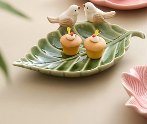 Close-up of green leaf-shaped ceramic tray with white bird accents for jewelry