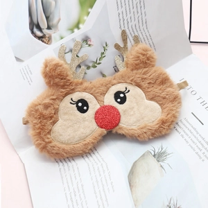 Cute plush reindeer sleep mask with gold antlers and red sequin nose on a magazine background