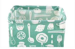 Detail of green cotton linen storage bin with white kitchen pattern and top handle