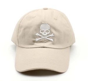 Detailed close-up of a khaki baseball cap featuring white skull embroidery and distressed brim
