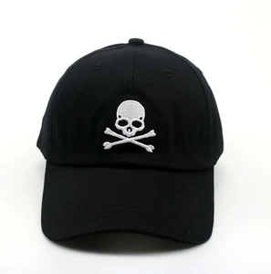 Detailed close-up of white skull and crossbones embroidery on black cotton baseball cap