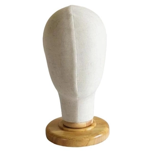 Linen covered mannequin head for wig and hat display with a round wooden base detail