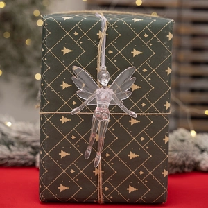 Close-up of a clear acrylic fairy ornament hanging on a green gift box with soft festive lights