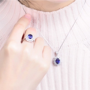 Elegant silver jewelry set with blue oval crystal necklace and ring on a model