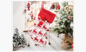 Close-up of a red and white knitted Christmas stocking with reindeer patterns and pom-poms