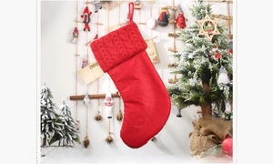 Reverse side view of red knitted Christmas stocking with cable knit cuff and festive decor