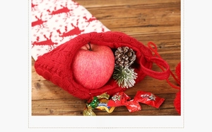 Detail of red and white knitted Christmas stocking filled with an apple and pine cone