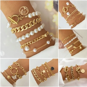 Detail of bohemian gold bracelet set with pearls, butterfly and star charms for women