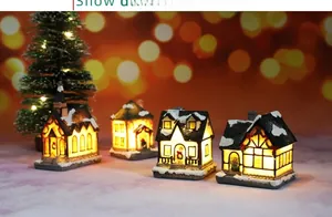 Close-up of four LED Christmas resin houses with warm lights and snow textures