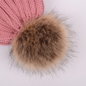 Pink winter knit beanie with fluffy brown faux fur pom pom on a white background