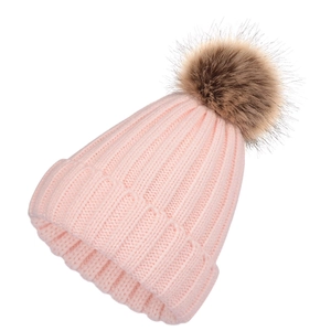 Detail of pink ribbed knit beanie featuring a large fluffy brown faux fur pompom top