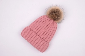 Close-up detail of pink ribbed knit beanie featuring a large faux fur pompom on top
